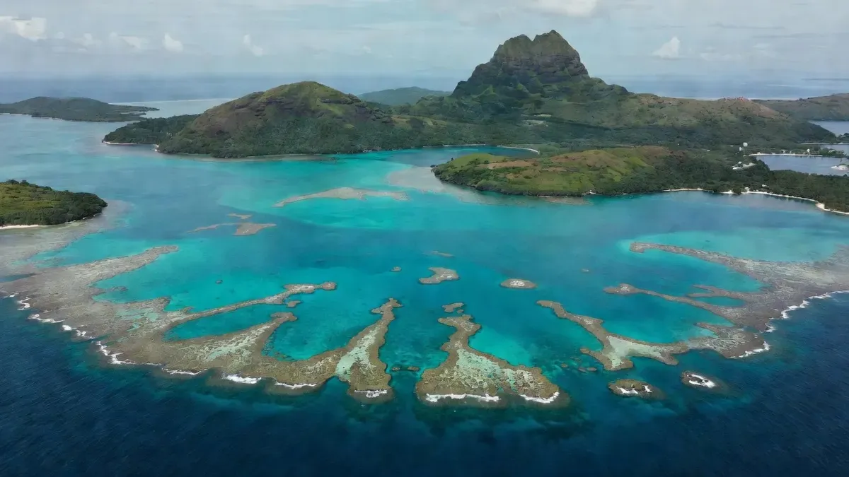 A panoramic view of Moorea's turquoise lagoon at sunrise with the volcanic peaks of French Polynesia rising in the background — the setting for some of the best snorkeling in the South Pacific